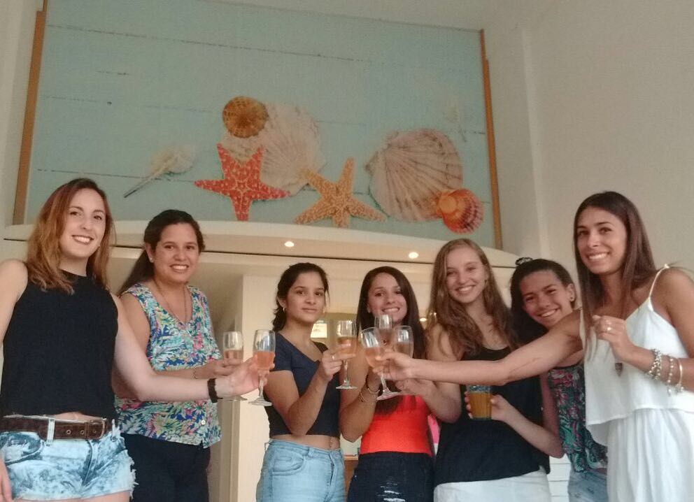 Un grupo de mujeres brinda en el spa, bajo el panel turquesa con estrellas de mar y caracolas